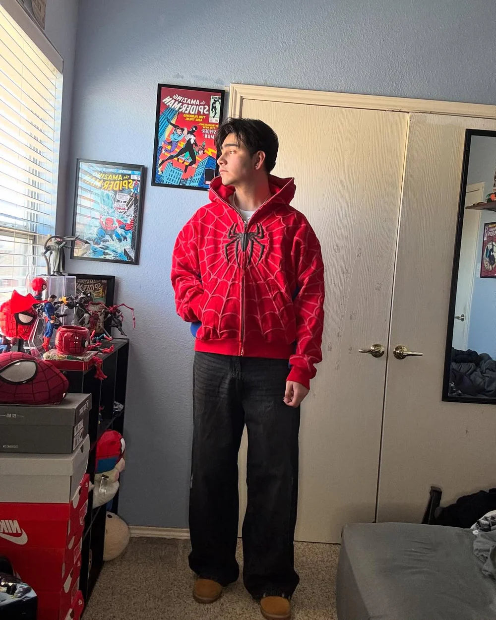Person wearing a Spider-Man hoodie in a room with superhero-themed decor