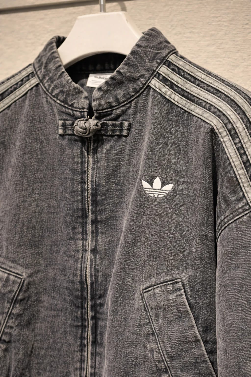 Denim jacket with Adidas logo on a hanger
